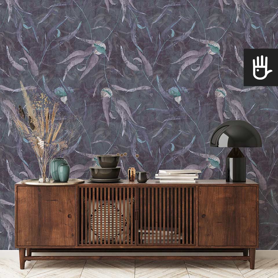 Elegancka drewniana komoda w stylu PRL na tle granatowej ściany w stylu vintage z położoną tapetą Turkusowe kwiaty eukaliptusa z malowanymi liśćmi w kolorze fioletowym.