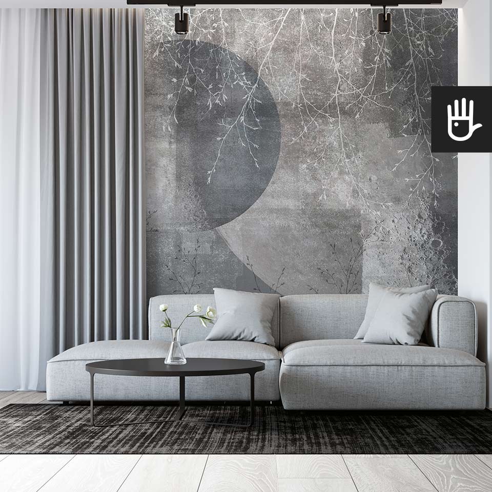 Minimalistyczne wnętrze salonu w stylu modern z szarą kanapą narożną na tle fototapety Srebrny księżyc z motywem astronomicznym i delikatnymi białymi gałązkami.
