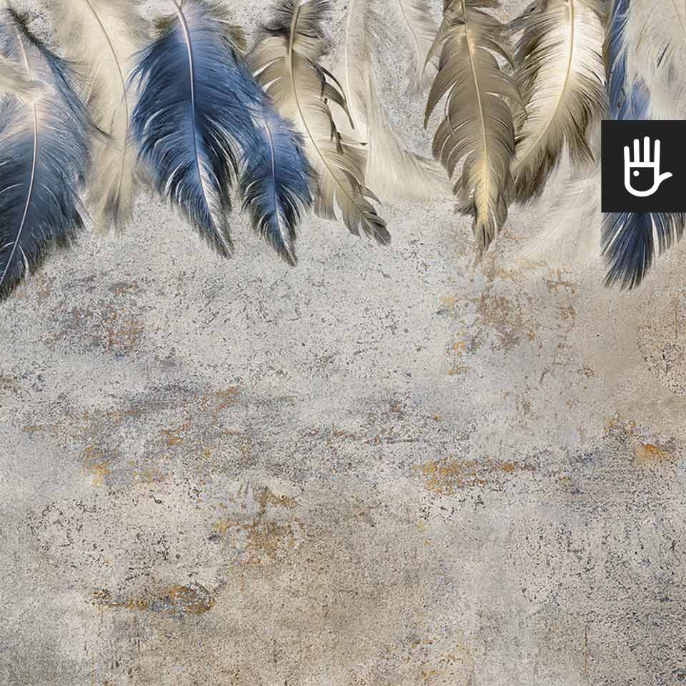 Fototapeta Niebieskie piórka z dekoracyjnymi, zwisającymi, granatowymi i złotymi piórami na tle dekoracyjnego tynku w kolorze szaro-beżowym.