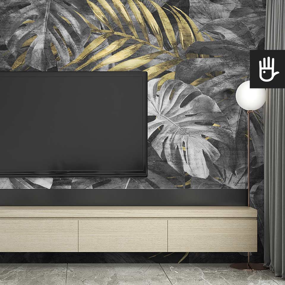 Nowoczesny salon z drewnianą szafką pod telewizorem i dekoracyjną lampą stojącą na tle fototapety monstera w złocie