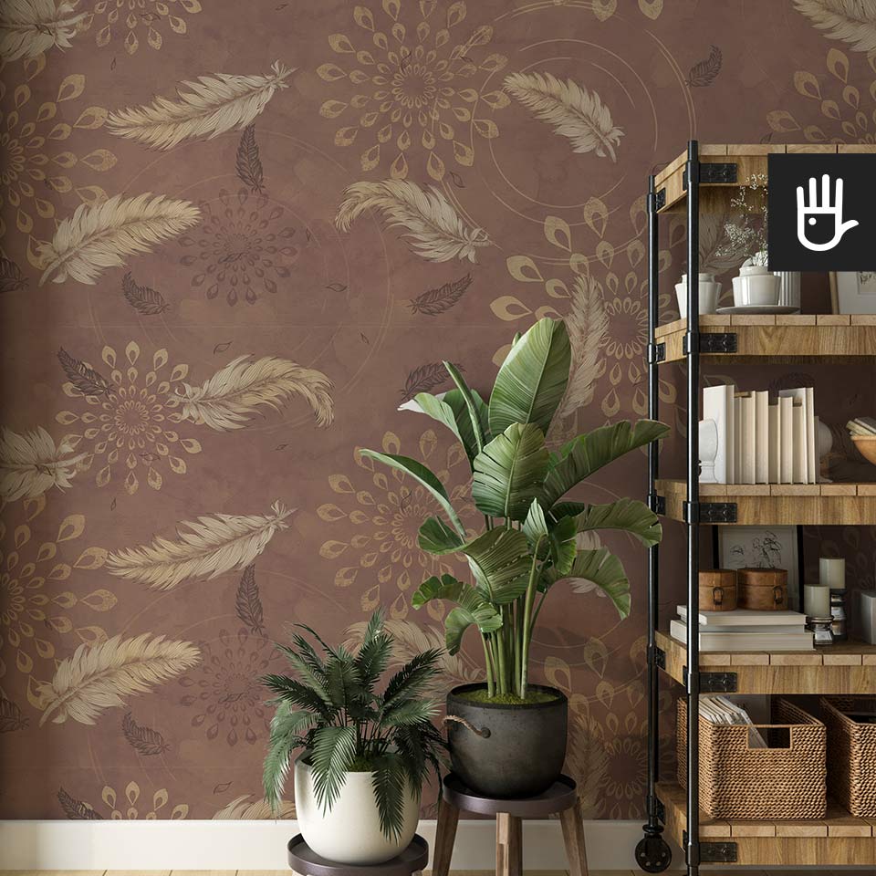 Drewniany regał zastawiony dekoracjami w stylu boho obok dekoracyjnych kwiatów na tle brązowej tapety w delikatne piórka ze wzorem mandali