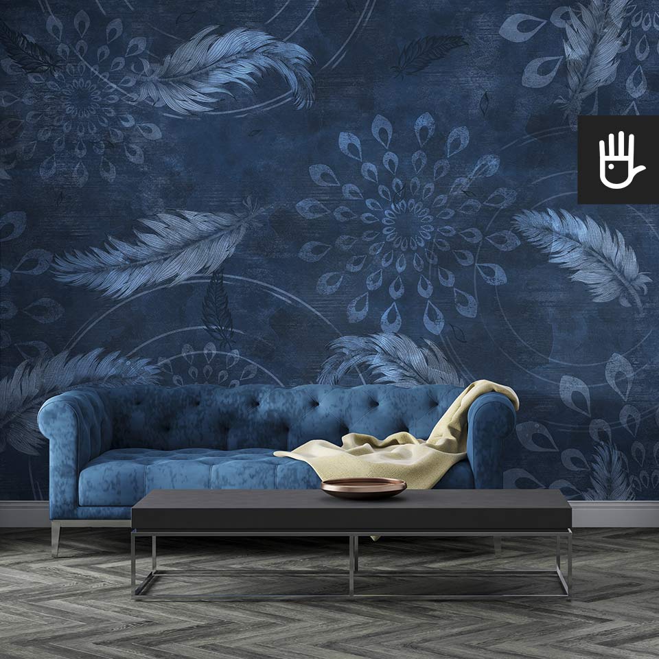 Nowoczesny salon w ciemnych kolorach a granatową pikowaną kanapą na tle tapety granatowe boho z delikatnymi piórkami