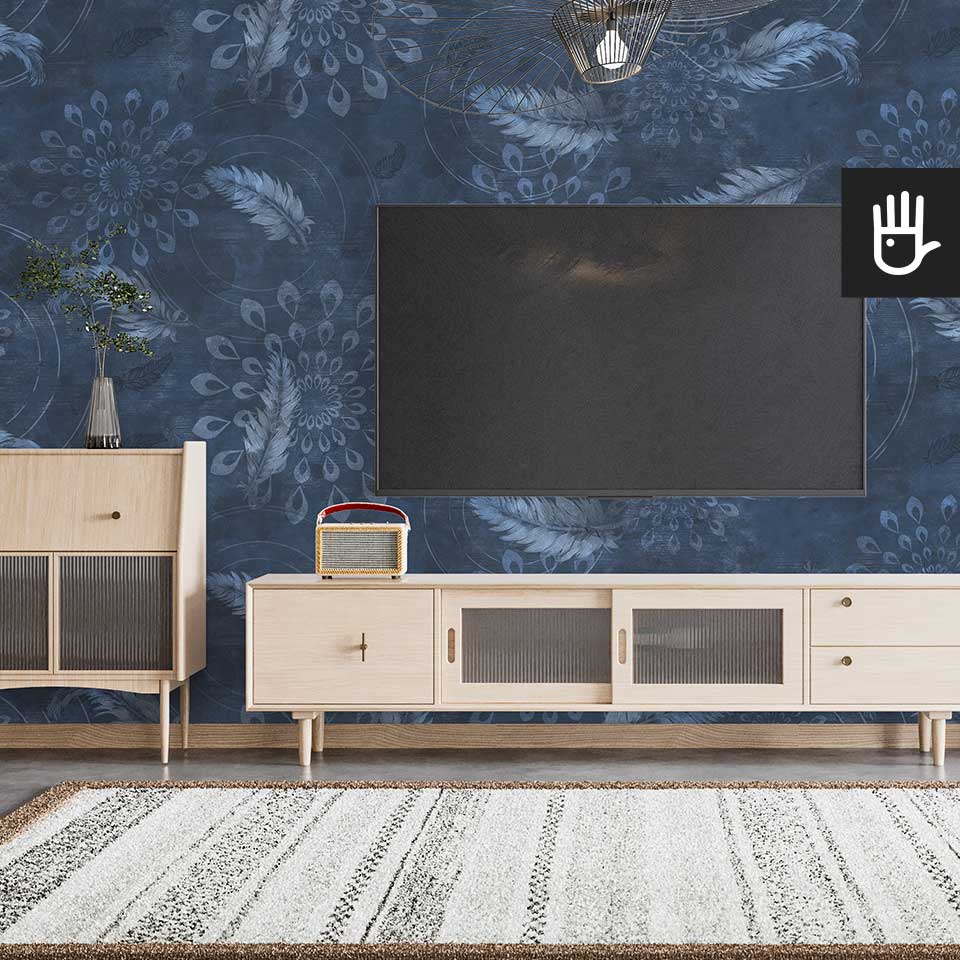 Salon urządzony w stylu boho z drewnianą szafką rtv i dywanem. Na ścianie telewizor na tle tapety w piórka