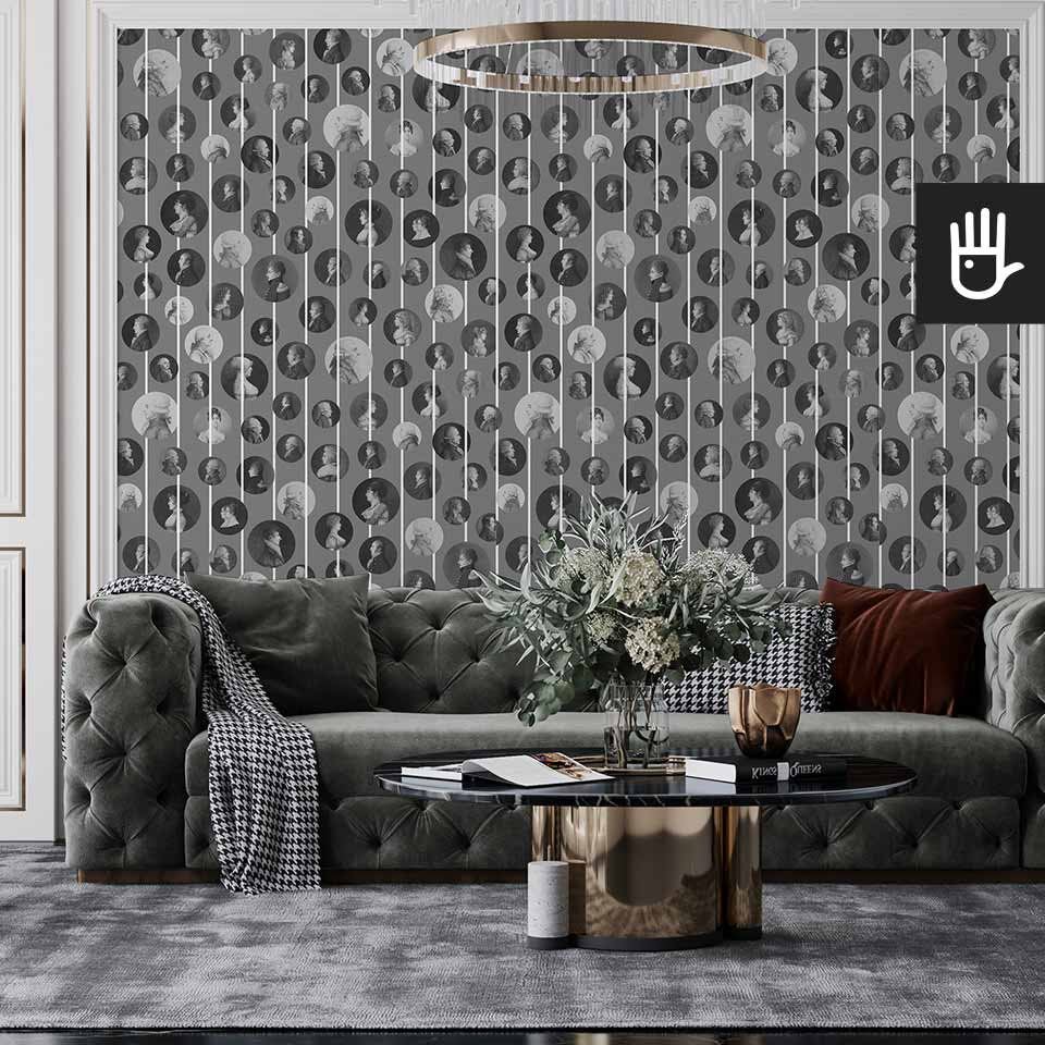 Klasyczny salon z szara pikowaną kanapą, urządzony w stylu glamour z wieloma złotymi dodatkami na tle tapety z podobiznami arystokratów
