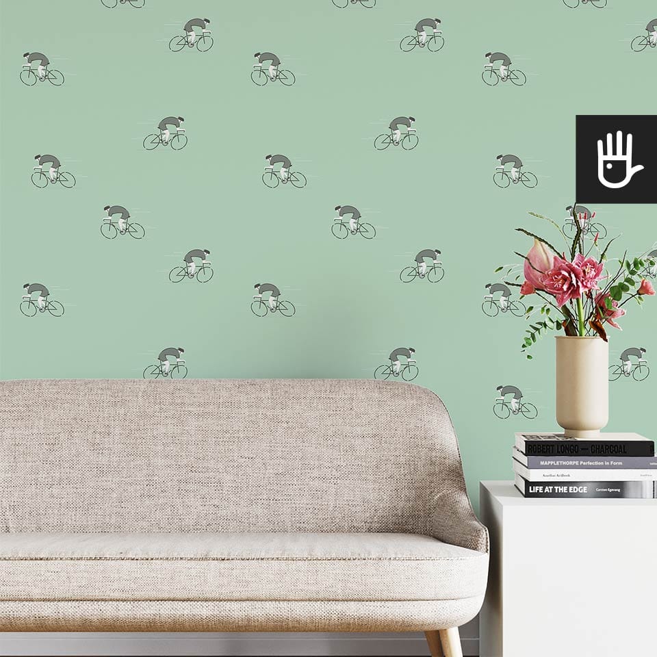 Jasny salon w stylu boho z beżową kanapą na tle tapety ze wzorem w zielonych kolarzy