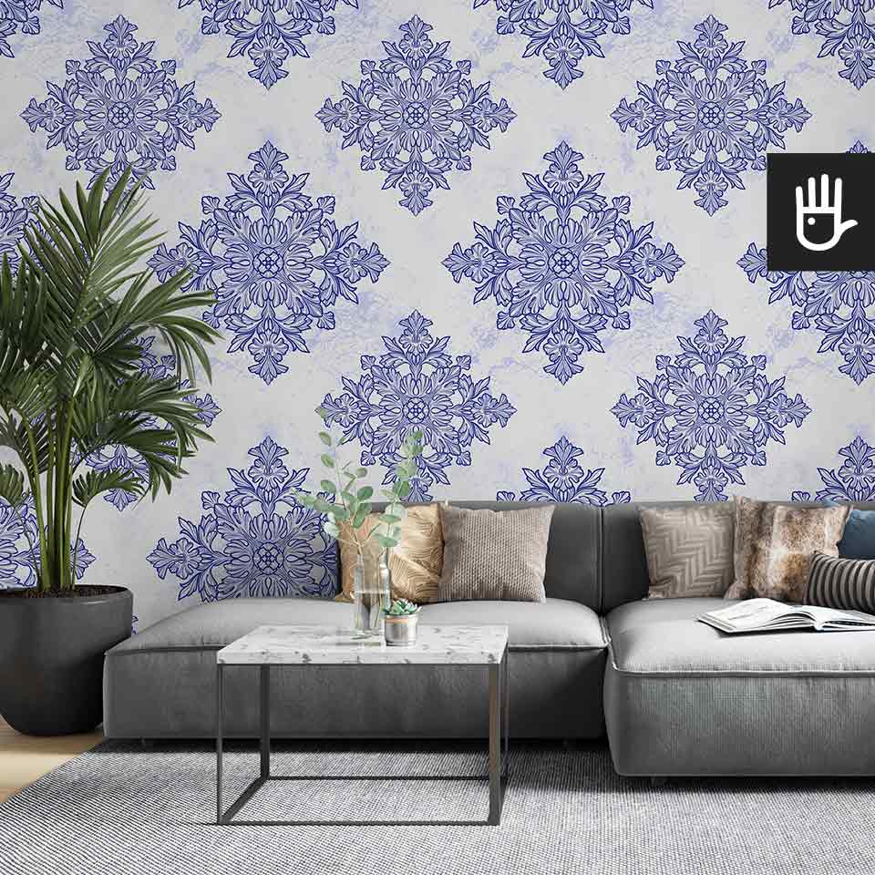 Jasny salon z szarą kanapą i ozdobnym kwiatem palmą ze stolikiem z imitacji marmuru na tle tapety w geometryczny wzór