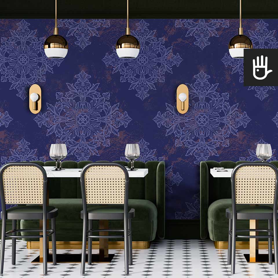 Restauracja w stylu retro z zielonymi kanapami i krzesłami z oparciami z ratanu na tle ciemnej tapety w geometryczny wzór