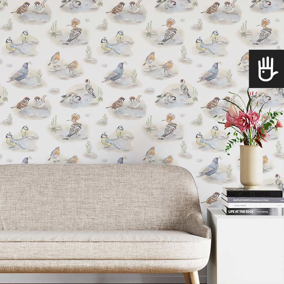 Jasny salon w stylu boho z beżową kanapą na tle tapety ze wzorem w kolorowe ptaki