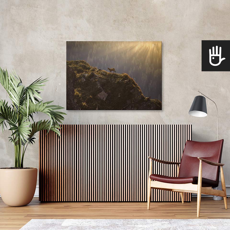 Salon w stylu retro z bordowym fotelem ze skóry i wielkim zielonym kwiatem na tle ściany ze strukturą betonu z przywieszonym obrazem przedstawiającym góry