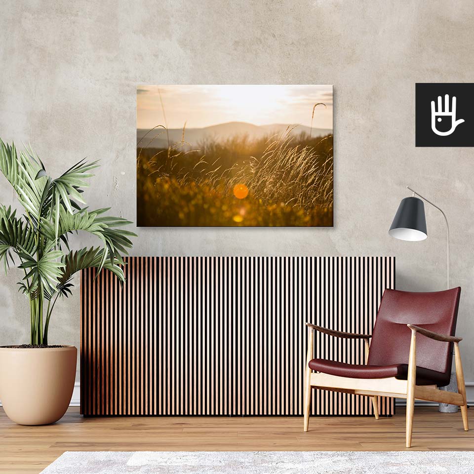 Salon w stylu retro z bordowym fotelem ze skóry i wielkim zielonym kwiatem na tle ściany ze strukturą betonu z przywieszonym obrazem przedstawiającym góry