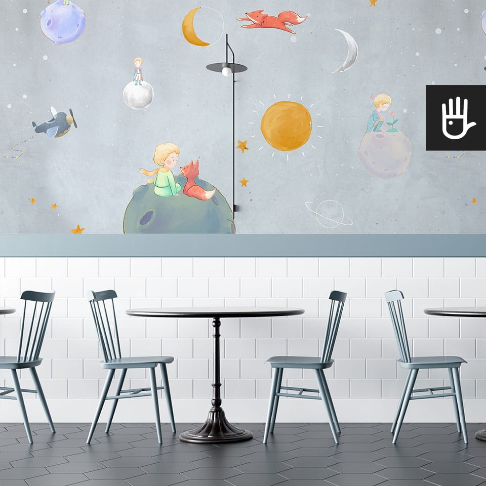 Stylowa restauracja z czarnymi stolikami i niebieskimi krzesłami ozdobiona tapetą z motywem małego księcia