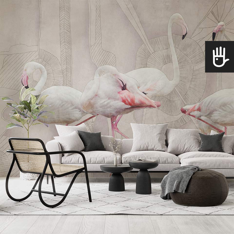 Nowoczesny salon z dużą beżową kanapą, czarnymi dekoracyjnymi stolikami kawowymi i ratanowym fotelem udekorowana abstrakcyjną fototapetą z flamingami