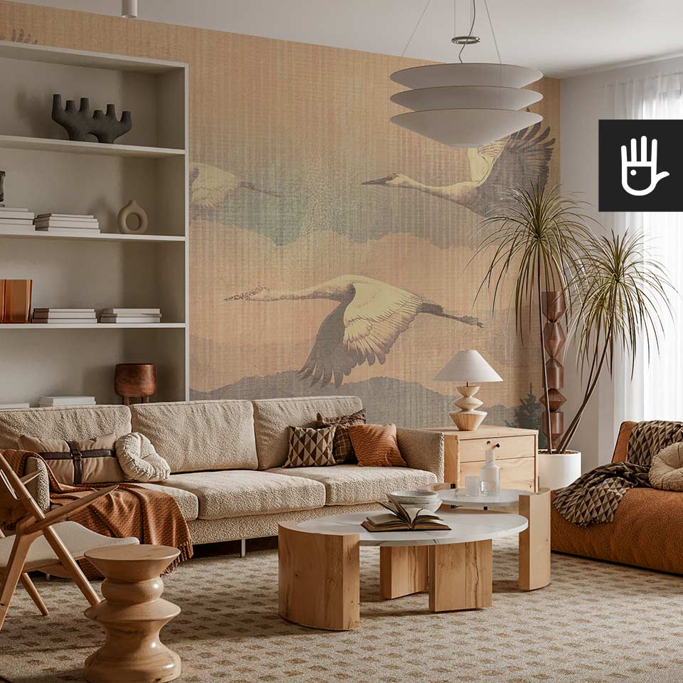 Przytulny salon w stylu boho z dwoma kanapami z barankowym materiałem i drewnianymi stolikami kawowymi na tle fototapety z lecącymi żurawiami nad lasem