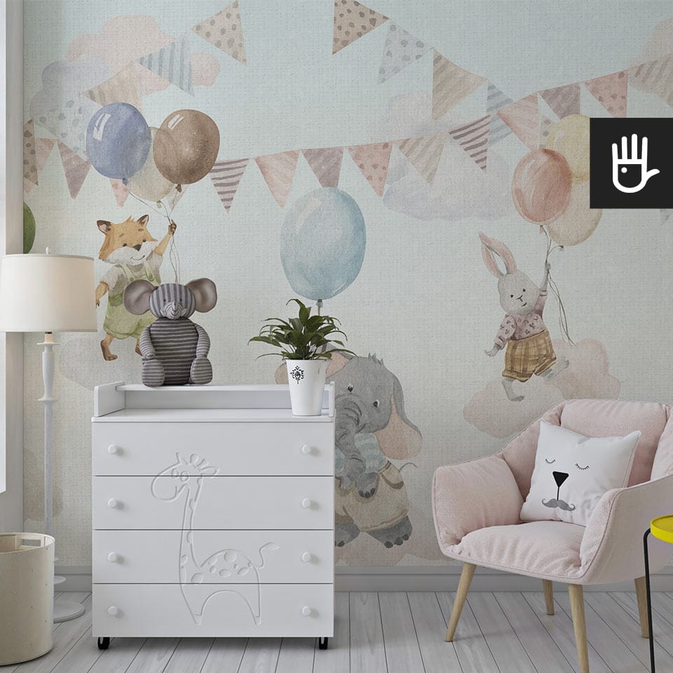 Przytulny pokój dziecięcy z różowym fotelem i białym regałem z żyrafą na tle fototapety z przyjaznymi zwierzątkami
