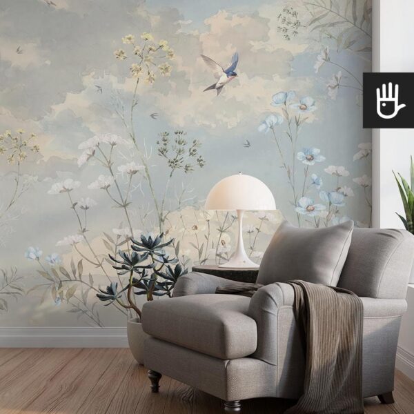 Przytulny salon z szarym fotelem i dekoracyjną lampą do czytania na tle fototapety niebiańska łąka z polnymi kwiatami i jaskółkami